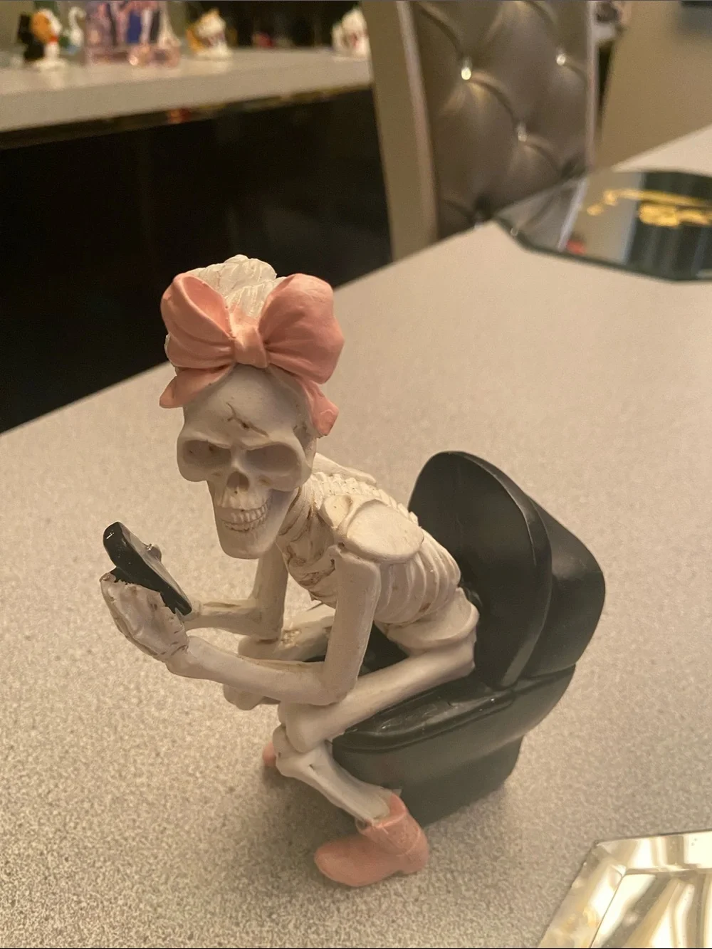 Pink-Bow Skeleton Figurine Sitting on Black toilet chair